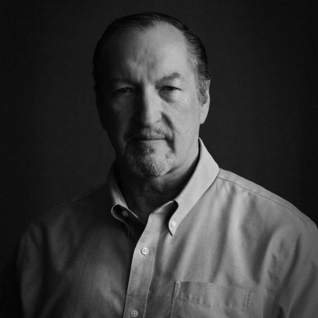 Portrait of a mature man with a serious expression, wearing a collared shirt, in black and white.