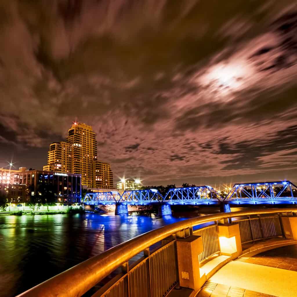 The full moon shines on the Grand River, the Blue Bridge and the Grand Rapids Museam.